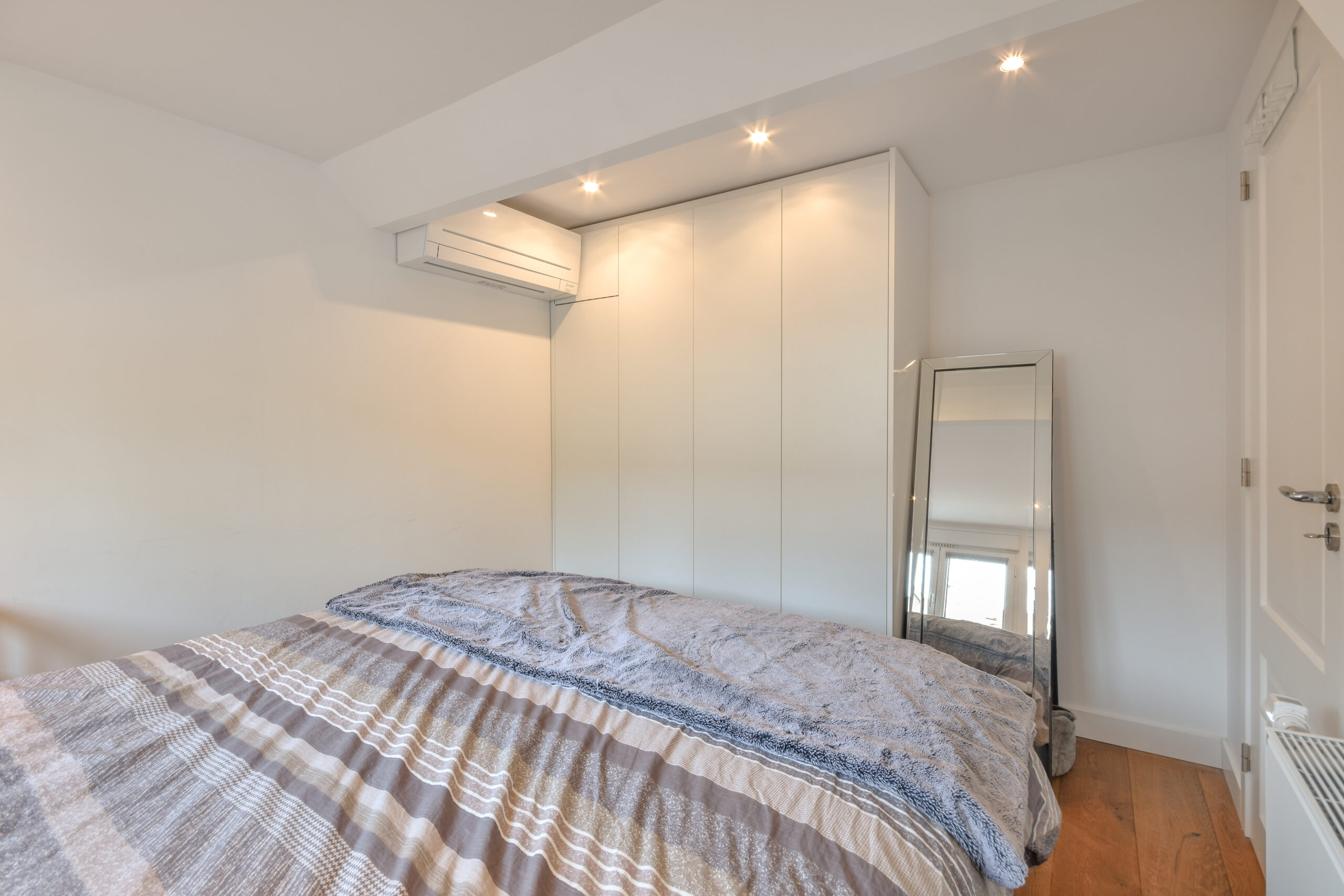 Modern bedroom with small window and wide bed