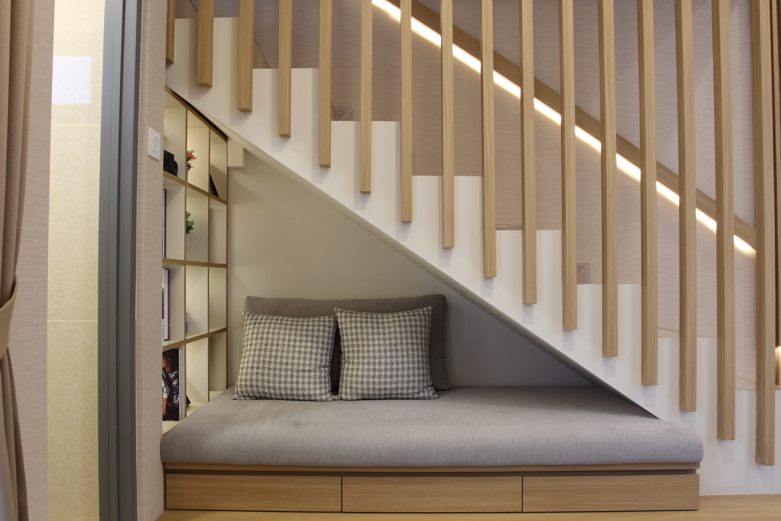 The sofa with some pillows under the staircase. Modern interior design.