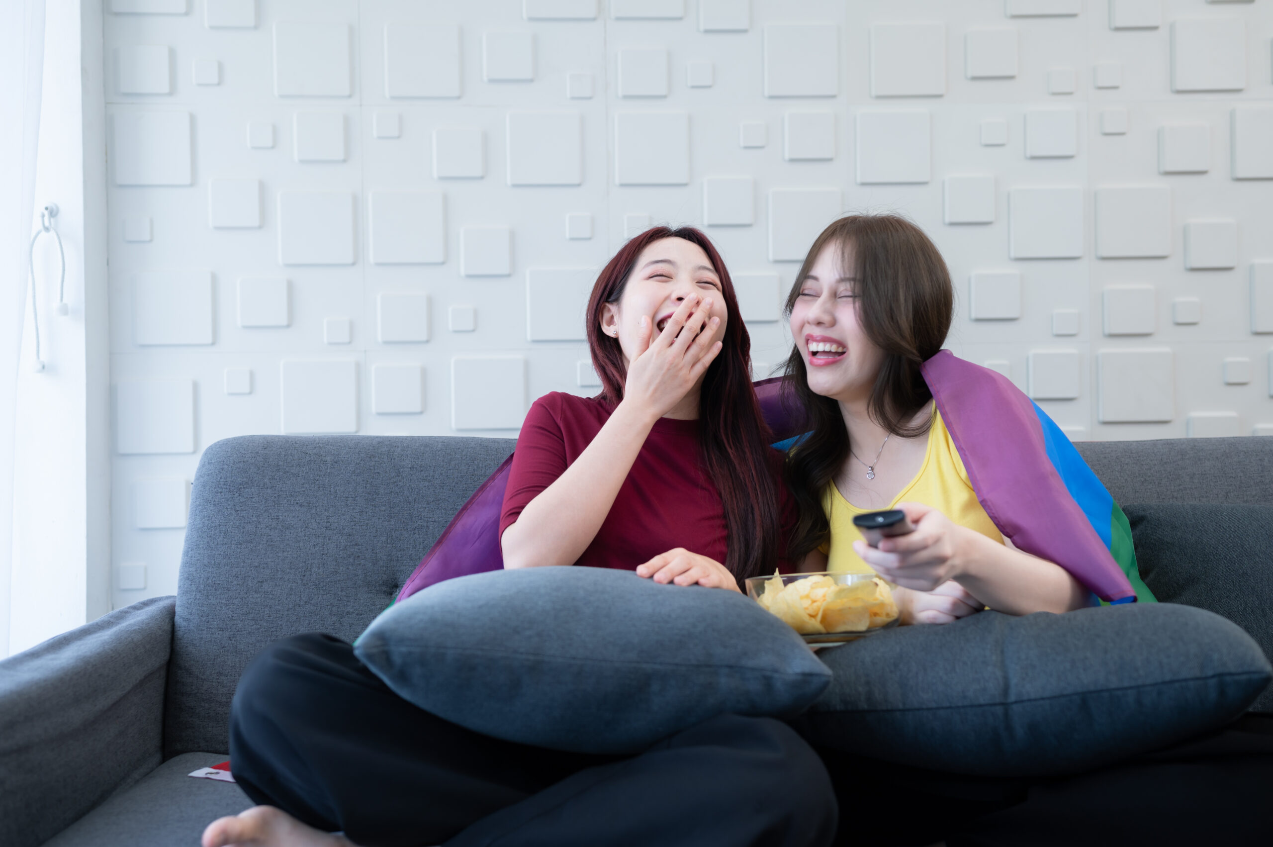 The LGBT couple watching a comedic drama on the sofa in the livi